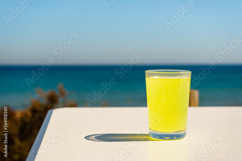 Citrus drink in glass on sea shore