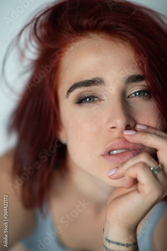 Beautiful young ginger woman with freckles and blue eyes. Portrait of charming girl wearing casual clothes posing at home, looking at camera