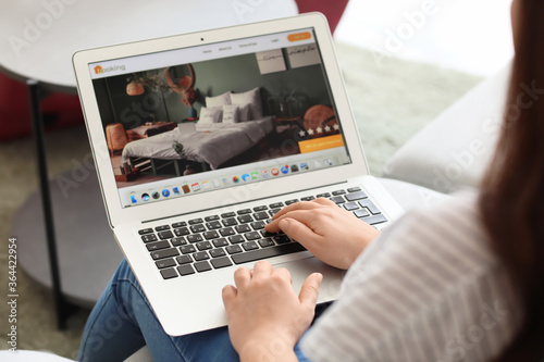 Woman with laptop booking room in hotel online at home