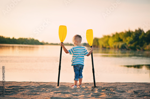 Little boy on the summer beach with oars Fototapet