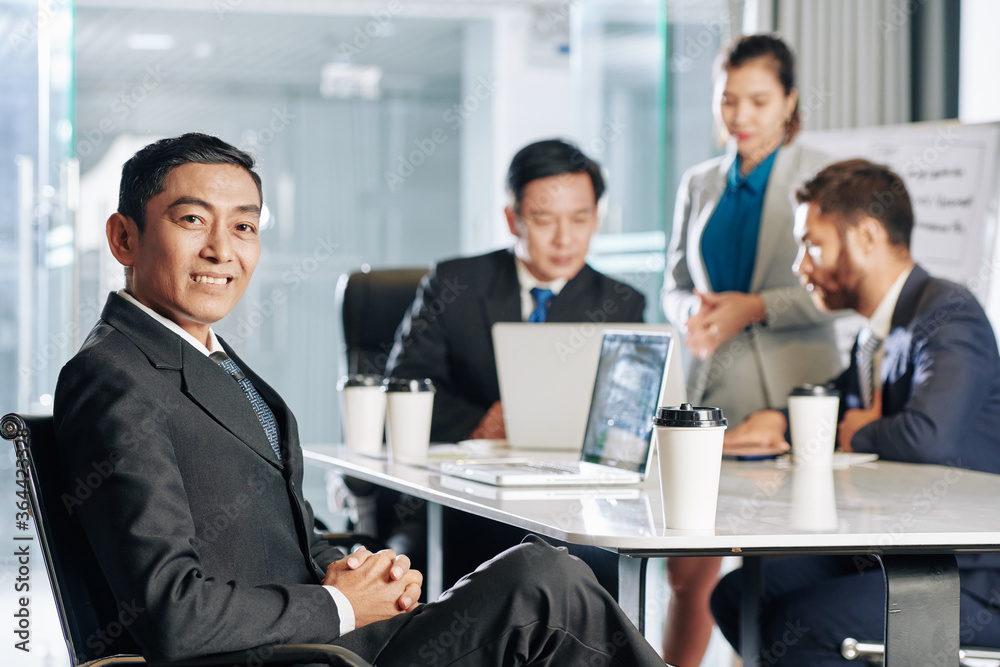 Portrait of smiling middle-aged entrepreneur meeting with colleagues in office Portrait of smiling middle-aged entrepreneur meeting with colleagues in office