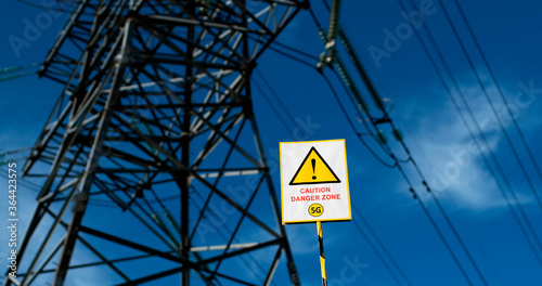 The “Warning 5G Hazardous Area” sign  against the background of a high voltage power line pillar.