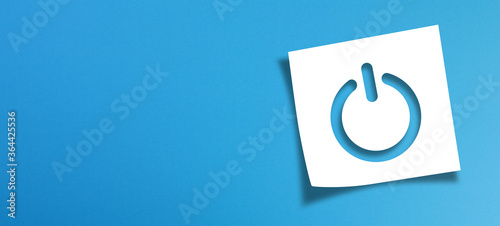Note paper and power button sign with copy space on panoramic blue background