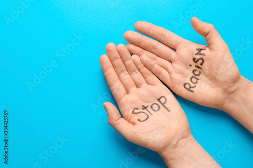 Female hands with written text STOP RACISM on color background