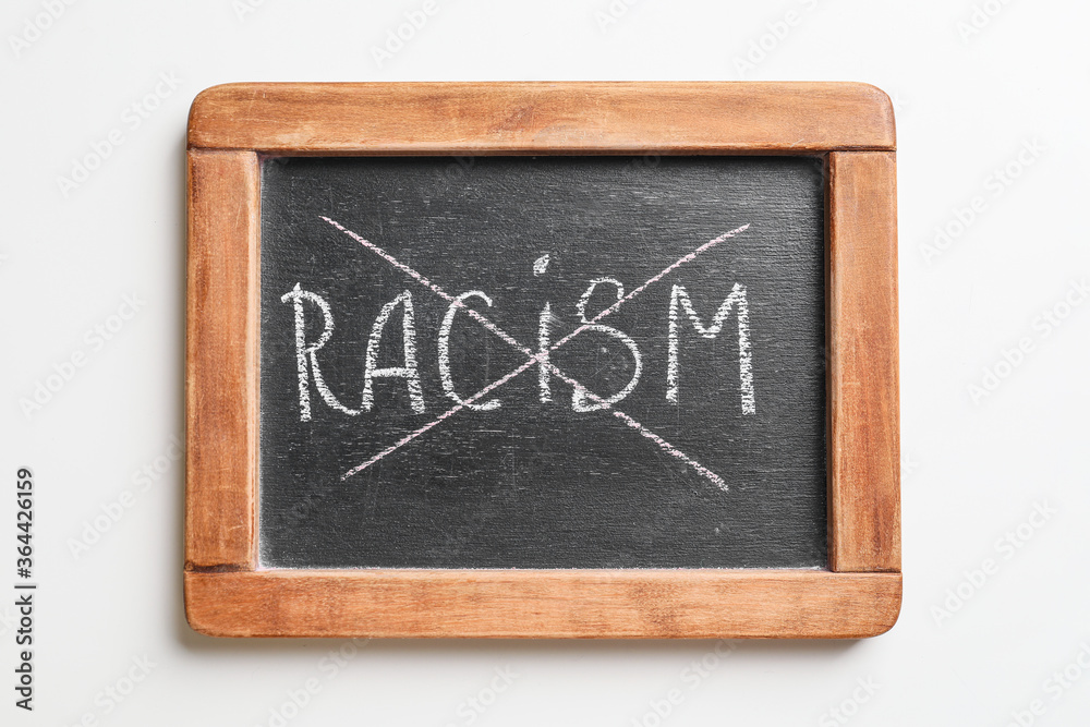 Chalkboard with crossed out word RACISM on white background Chalkboard with crossed out word RACISM on white background