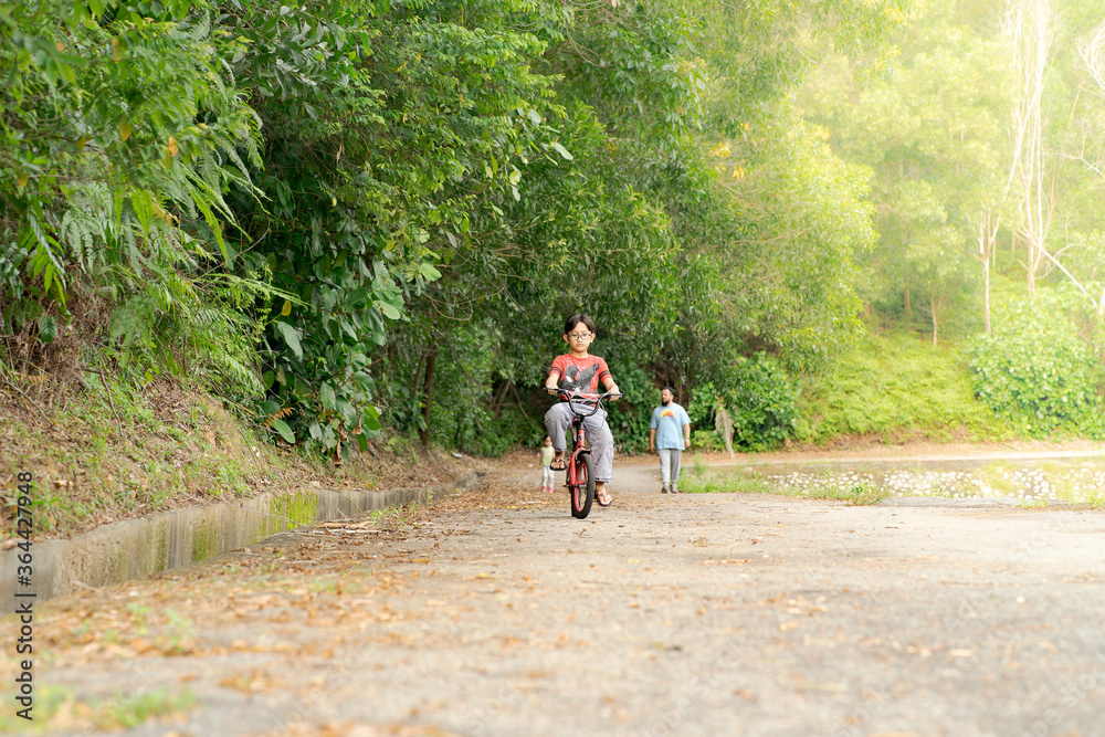 Child boy on a bicycle in the tropical forest. Boy cycling outdoors.
