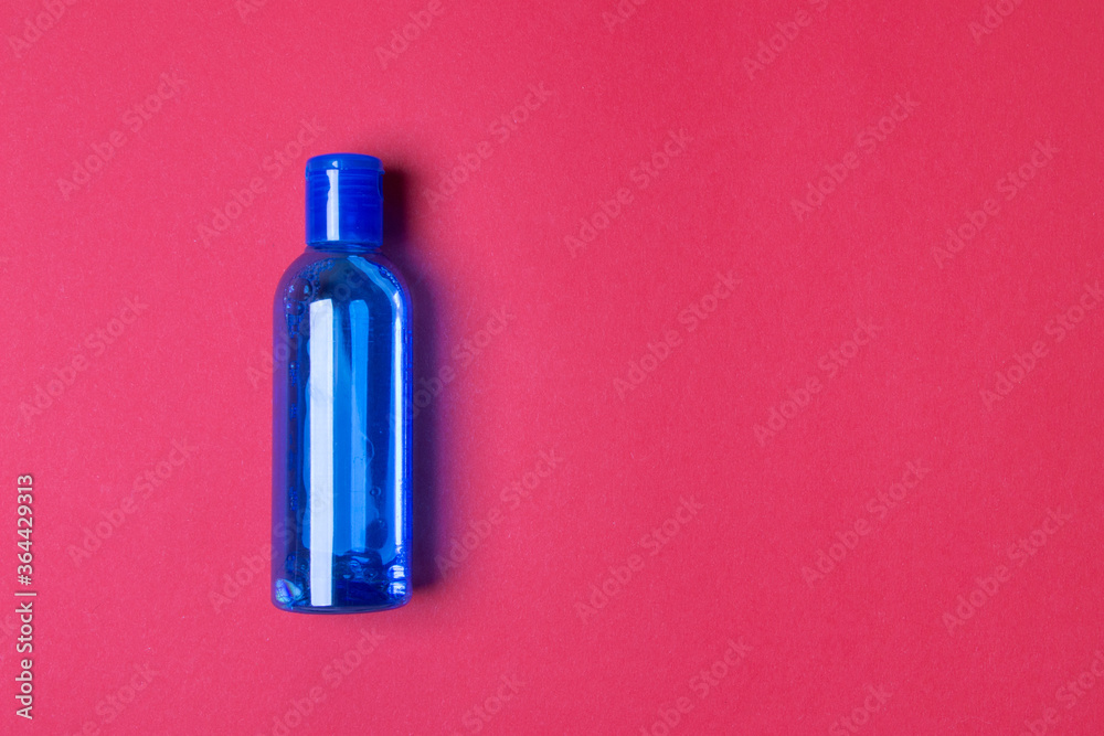 blue bottle with lotion on red colored paper background with copy space blue bottle with lotion on red colored paper background with copy space