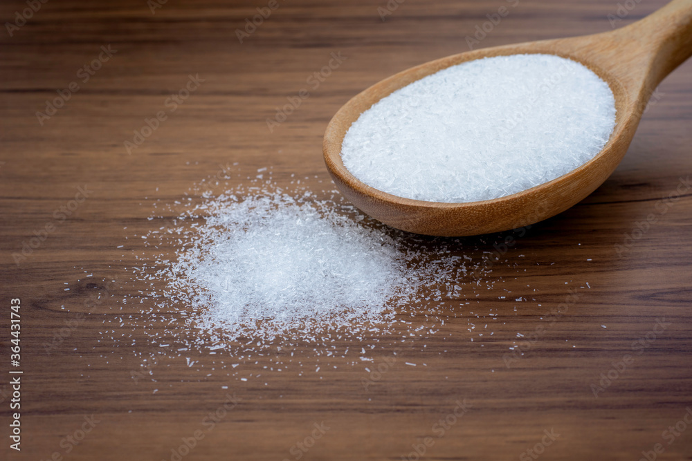 Monosodium glutamate ( MSG ) in wooden spoon isolated on rustic wood table background. Monosodium glutamate ( MSG ) in wooden spoon isolated on rustic wood table background.