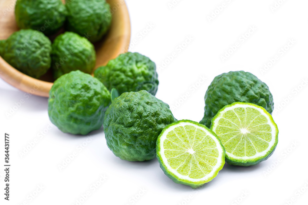Bergamot fruit or kaffir lime fruits in wooden bowl pouring on white background. Herbs medicine plant concept. Bergamot fruit or kaffir lime fruits in wooden bowl pouring on white background. Herbs medicine plant concept.