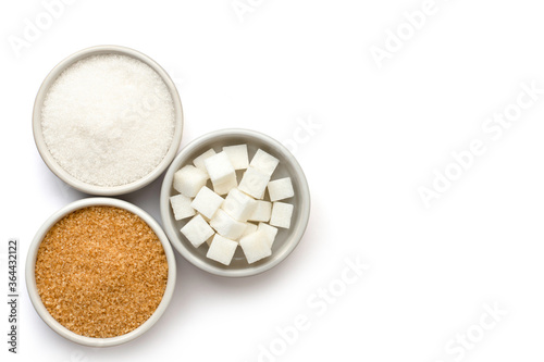 Three various types of sugar(sugar cubes,brown granulated sugar and white sand sugar) in bowl and spoon isolated on white background. Top view.Flat lay. Copy space for text and content.  