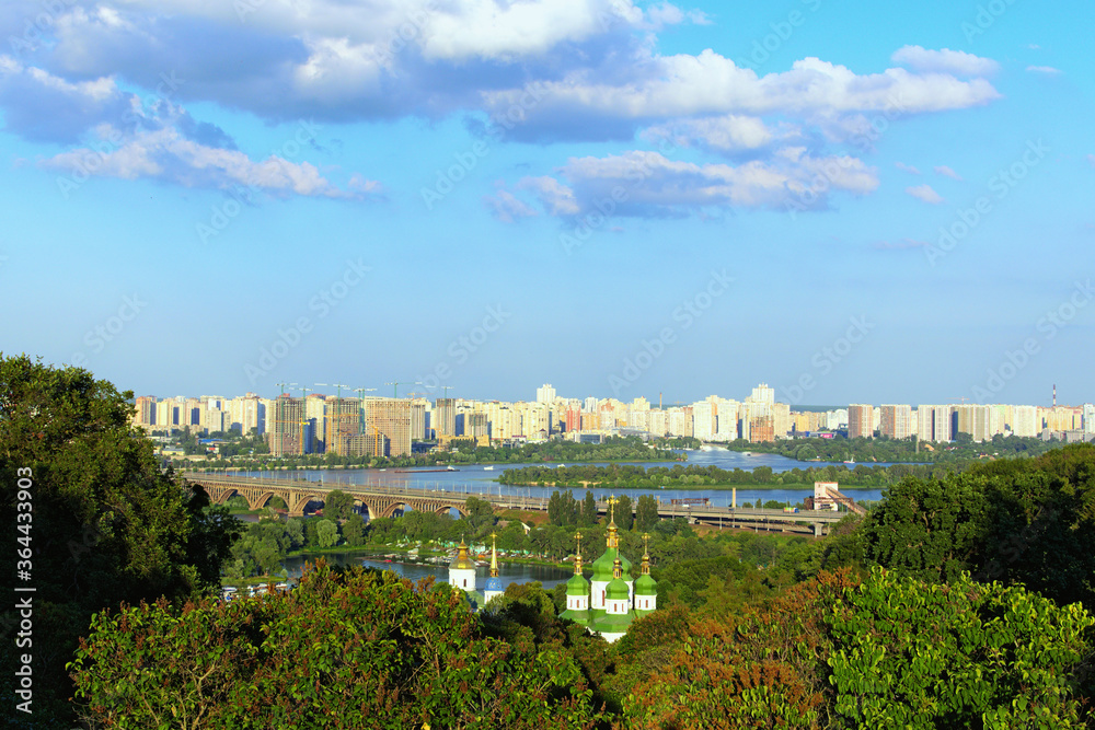 Picturesque landscape view of ancient Vydubychi Monastery, Dnipro River and construction of high-rise houses on the left bank of Dnipro. View from Hryshko National Botanical Garden. Kyiv, Ukraine