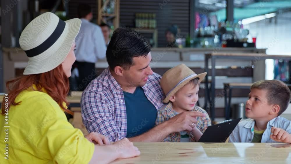 portrait of joyful happy family of parents with children have fun at table in cafe and choose food and drinks from restaurant menu portrait of joyful happy family of parents with children have fun at table in cafe and choose food and drinks from restaurant menu