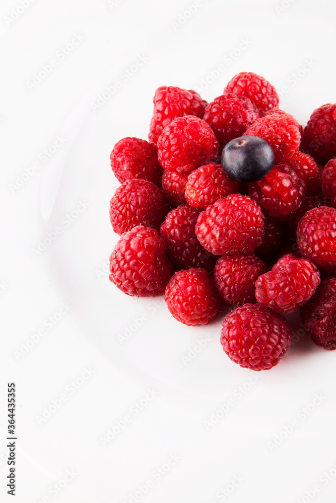 One blueberry on bed of raspberries One blueberry on bed of raspberries