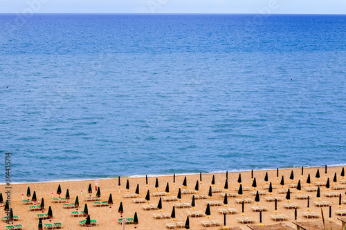 view of  a blue sea and a beach equipped with closed umbrellas in Italy