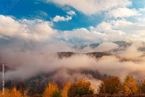 Foggy mountains under sky with clouds.