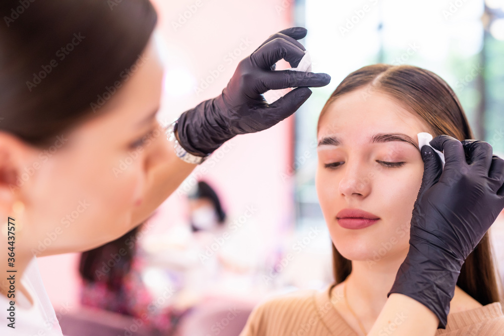 Fototapeta premium Brow artist clean face with sponge professional of young woman brow