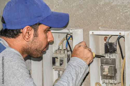 a professional electrician man is fixing the critical wiring connections of a electrical circiut board photo