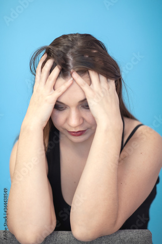 Young attractive caucasian woman holding head with both hands in despair position. Concept of problem, sadness. Female ungroomed, with grease make up, all skin imperfection are visible. Copy space. © Elena