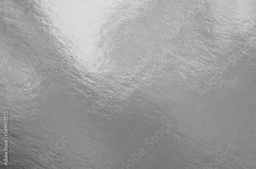 Silver foil texture background with highlights and uneven surface