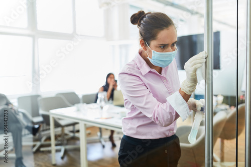 Putzfrau mit Mundschutz bei der Glas Reinigung im Büro