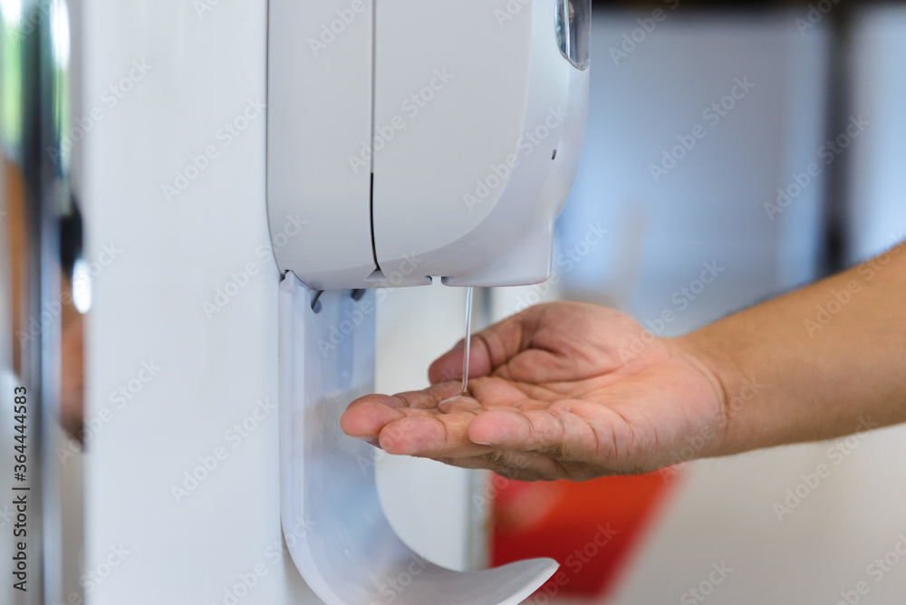 Photo close up hand male under automatic alcohol gel dispenser for cleaning hand and clear bacteria for stop Covid 19 virus outbreak bigy9950 Posters tableaux et papiers peints Europosters