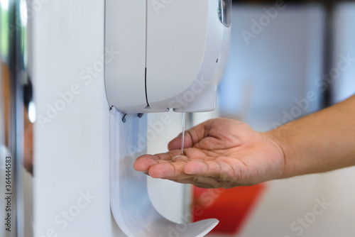 close-up hand male under automatic alcohol gel dispenser for cleaning hand and clear bacteria for stop Covid 19 virus outbreak. Protection against the virus, Covid-19, corona virus 2019