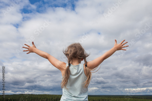 Carefree child girl against skyline sky clouds outdoor