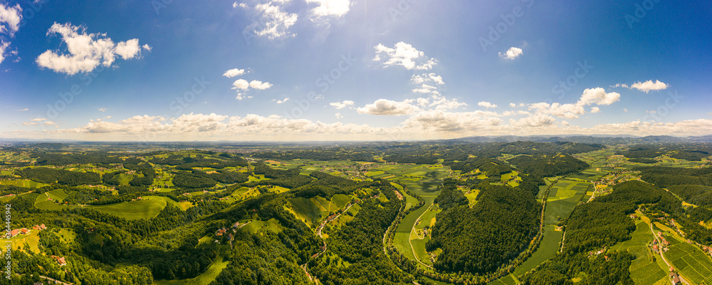 Aerial panorama of of green hills and vineyards with mountains in background. Austria vineyards landscape in Kitzeck im Sausal