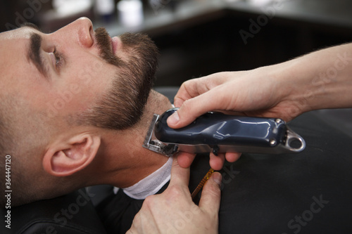 Cropped close up of a handsome bearded man getting his beard styled at the barbershop