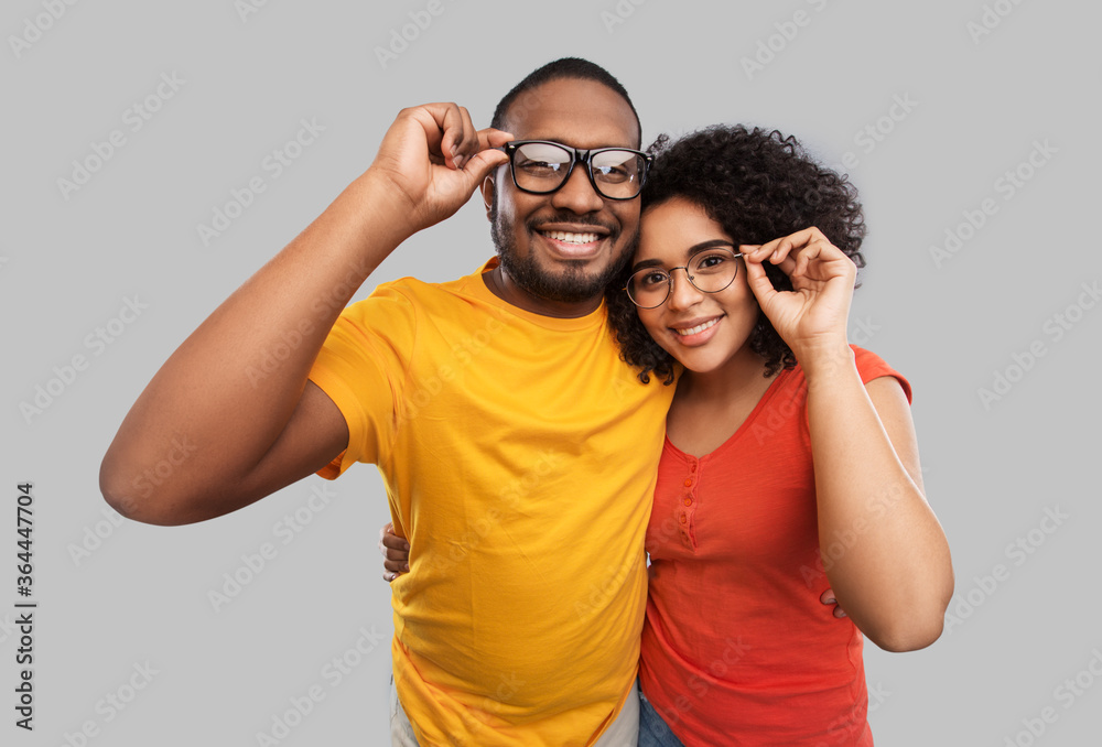 relationships, vision and people concept - happy african american couple in glasses hugging over grey background relationships, vision and people concept - happy african american couple in glasses hugging over grey background