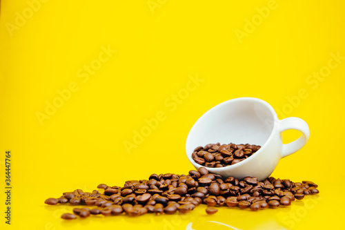 Coffee beans and a white Cup on a bright yellow background