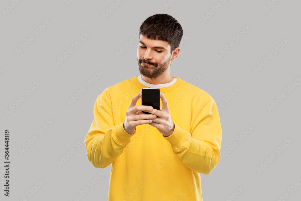 technology, communication and people concept - puzzled young man with smartphone over grey background technology, communication and people concept - puzzled young man with smartphone over grey background