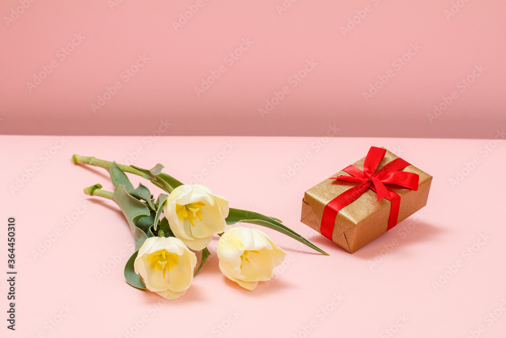 Gift box with tulip flowers on a pink background.