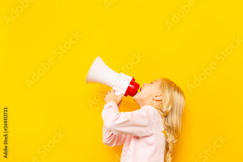 Kid shouting through megaphone. Communication concept. yellow background as copy space for your text
