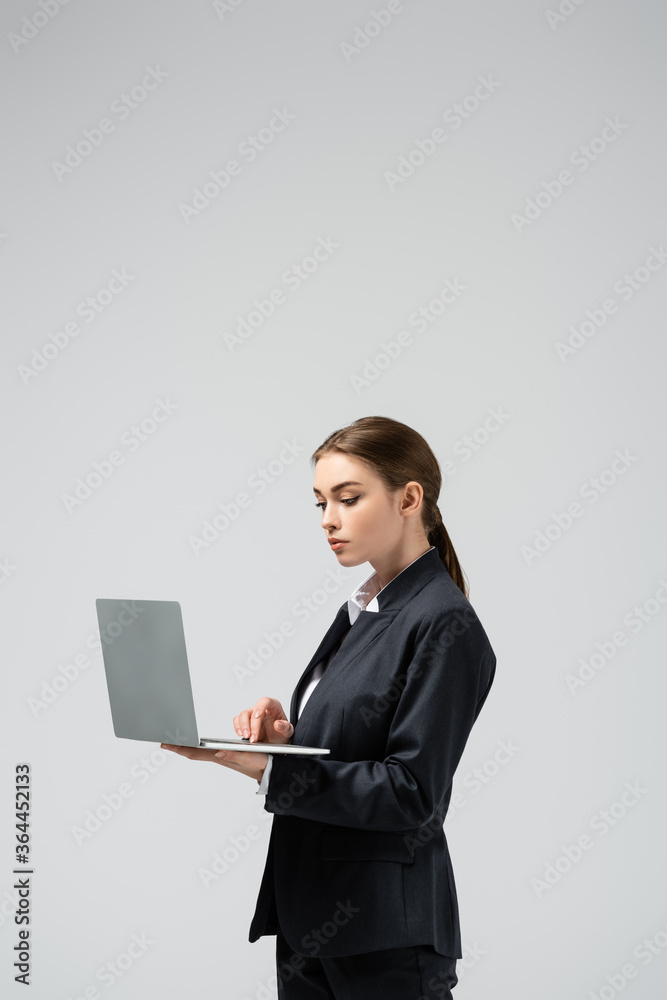 serious young businesswoman using laptop isolated on grey serious young businesswoman using laptop isolated on grey