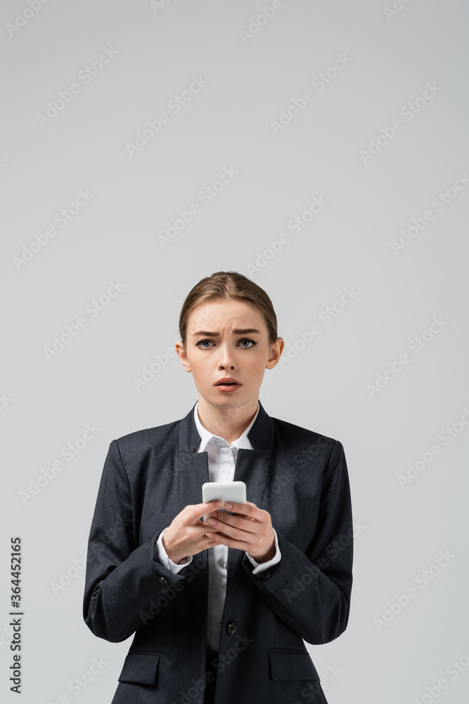 sad young businesswoman using smartphone isolated on grey sad young businesswoman using smartphone isolated on grey