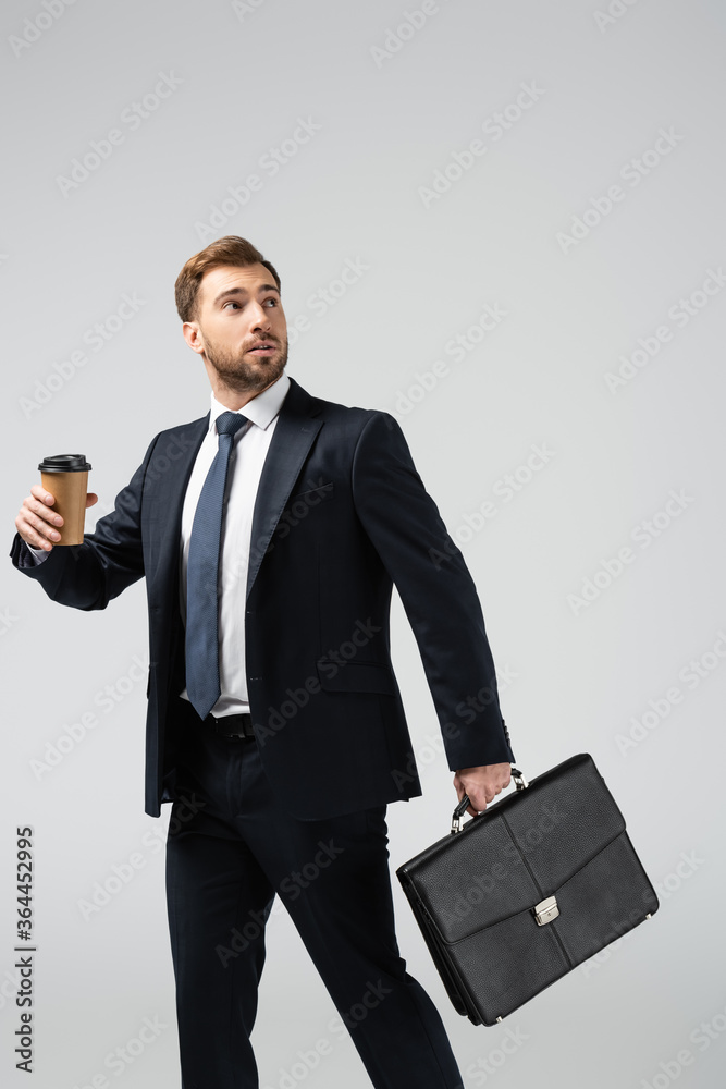 businessman with leather suitcase and paper cup looking away isolated on grey businessman with leather suitcase and paper cup looking away isolated on grey