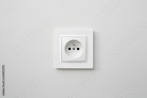 Brand new electrical socket isolated on gray wall. Renovated studio apartment power supply background. Empty copy space white plastic power outlet.