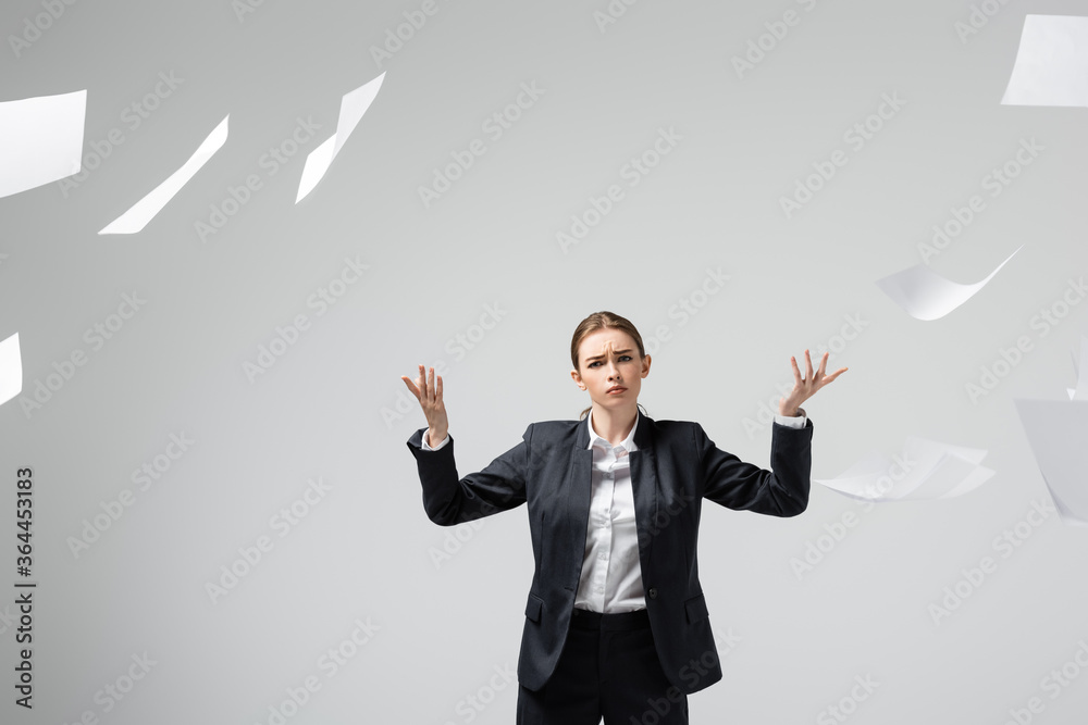 displeased businesswoman in suit throwing papers in air isolated on grey displeased businesswoman in suit throwing papers in air isolated on grey