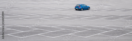 Blue car in an empty parking lot. Horizontal banner with copy space. family sedan without brand.