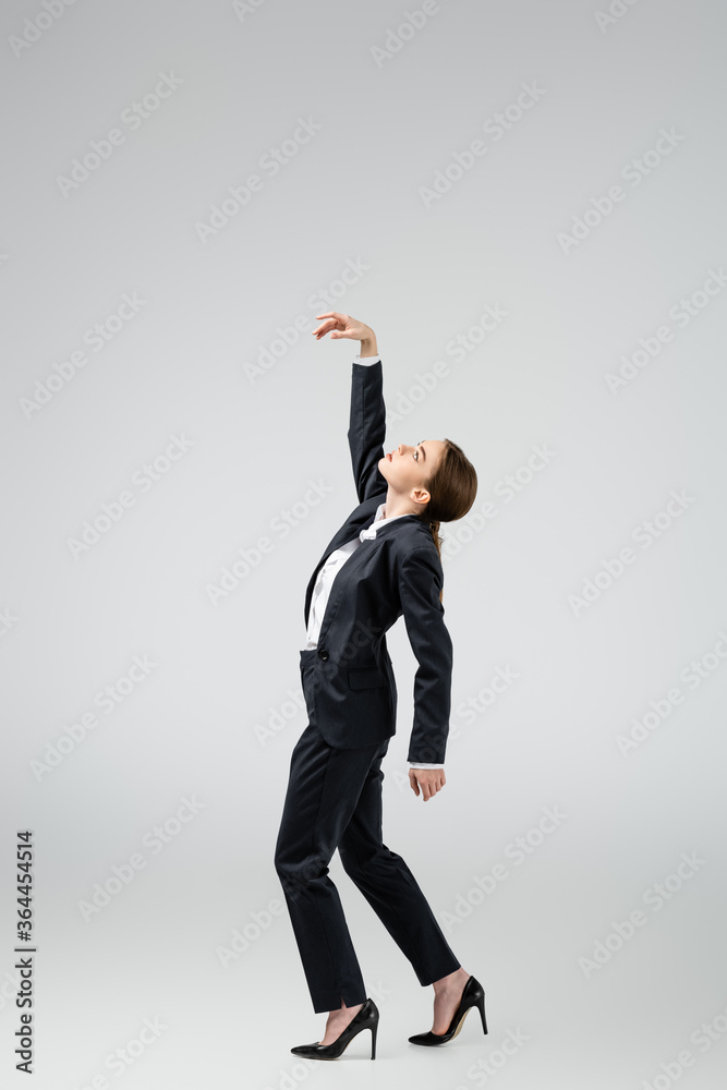 Φωτογραφία side view of businesswoman marionette in suit posing isolated on grey