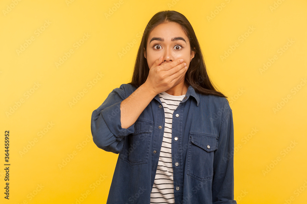 I won't tell anyone! Portrait of terrified girl in denim shirt covering mouth and looking frightened, holding breath shocked by terrible secret, intimidated and scared to talk. studio shot, isolated I won't tell anyone! Portrait of terrified girl in denim shirt covering mouth and looking frightened, holding breath shocked by terrible secret, intimidated and scared to talk. studio shot, isolated