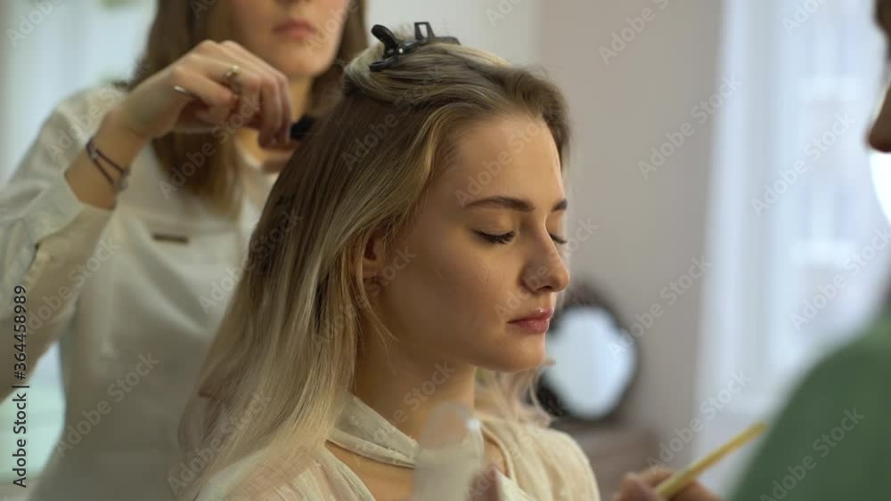 Middle shot portrait of young beautiful woman sitting in front of mirror and getting professional service in beauty salon. Concept of work make-up artist and hairdresser. Shooting in slow motion. Middle shot portrait of young beautiful woman sitting in front of mirror and getting professional service in beauty salon. Concept of work make-up artist and hairdresser. Shooting in slow motion.