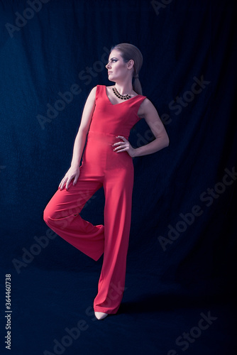 Young Blonde Dressed in Red Overalls Looking Away in Profile, on Deep Blue Background. Fashion Position