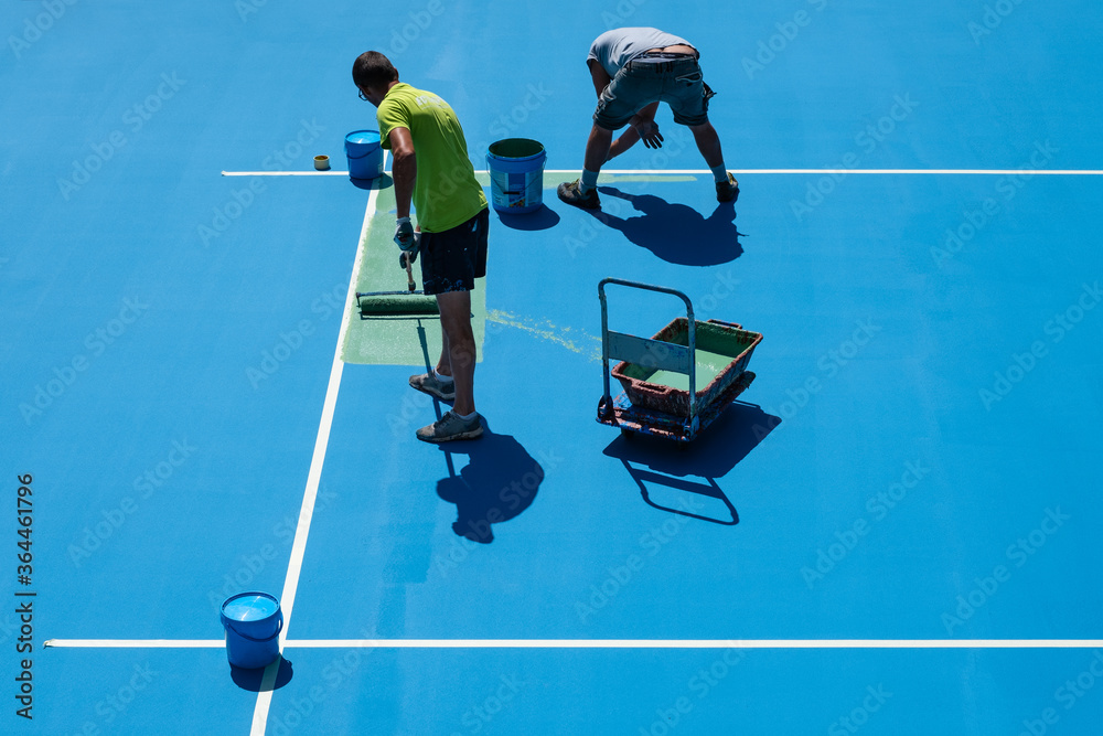 Operai al lavoro mentre dipingono un campo sportivo