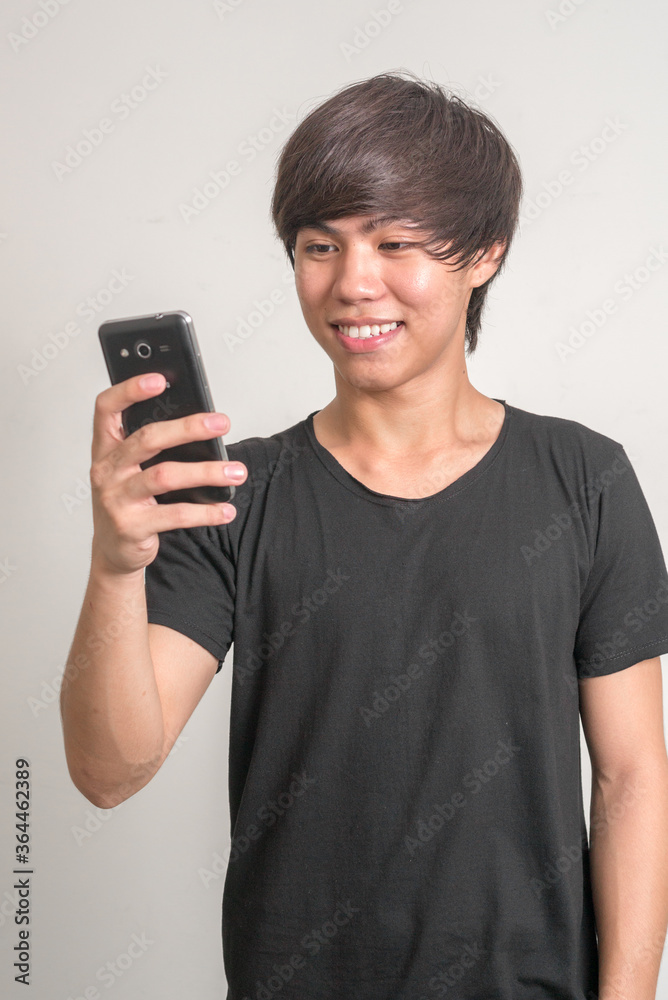Portrait of happy young Filipino man using phone Portrait of happy young Filipino man using phone