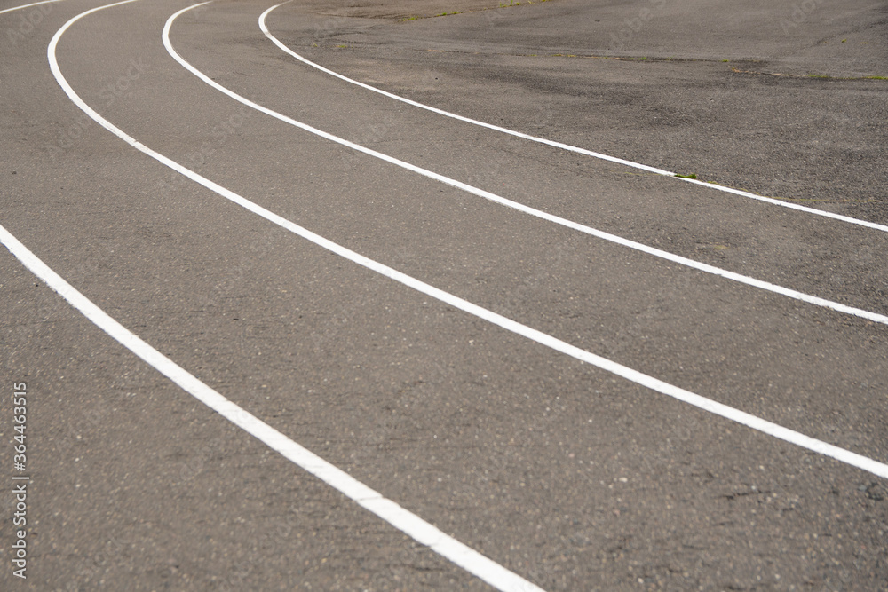 white markings for running in a sports stadium. outdated asphalt pavement at the stadium. white markings for running in a sports stadium. outdated asphalt pavement at the stadium.