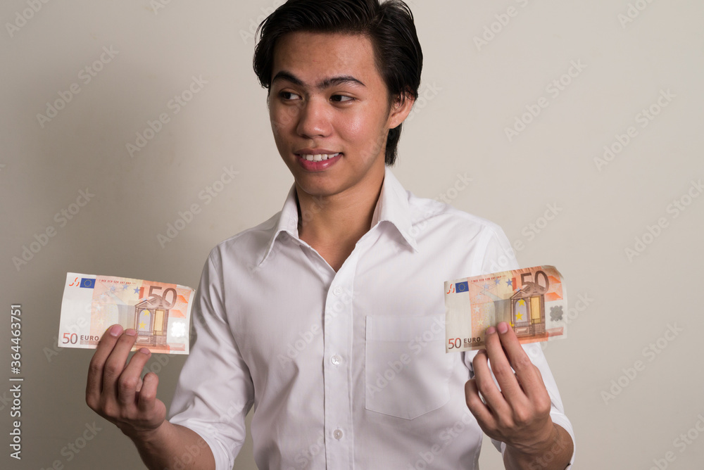 Portrait of happy young Filipino businessman holding money Portrait of happy young Filipino businessman holding money