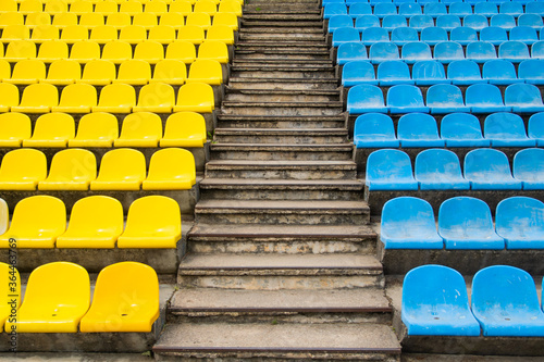 empty bright yellow and blue seats for fans at the football stadium in the summer between the stairs