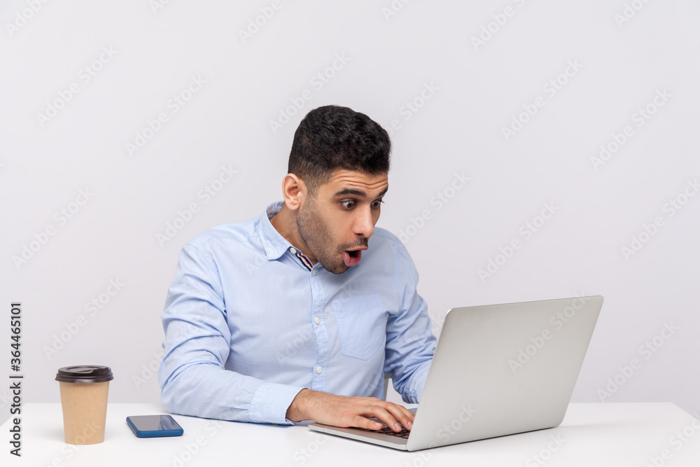Oh my god, wow! Amazed businessman sitting office workplace looking at laptop screen with surprised expression, talking on video call, reading shocking news. studio shot isolated on white background Oh my god, wow! Amazed businessman sitting office workplace looking at laptop screen with surprised expression, talking on video call, reading shocking news. studio shot isolated on white background